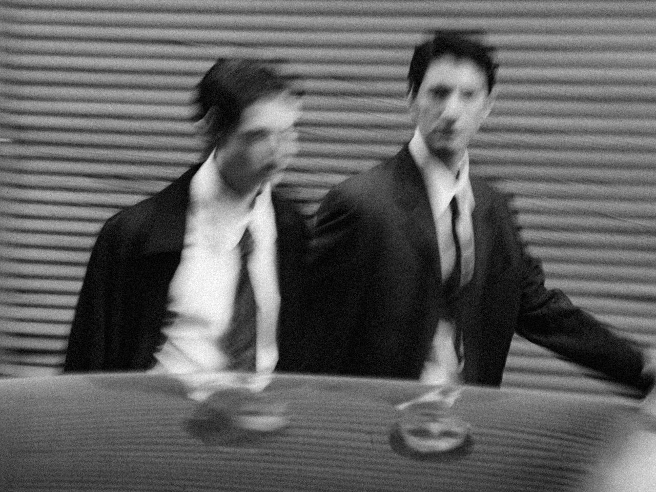 Two men in suits walking past, black and white