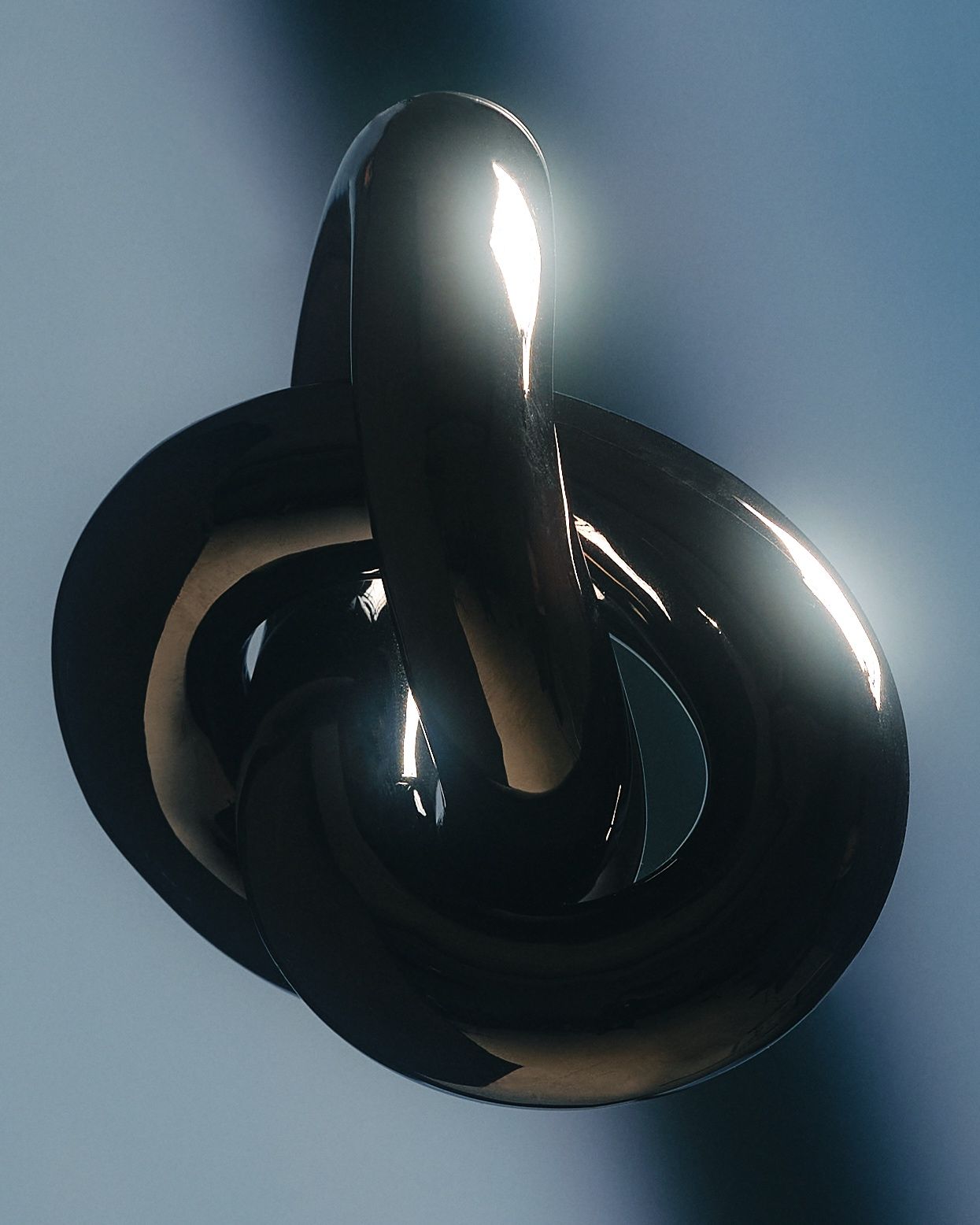 Glossy black sculptural form on deep blue